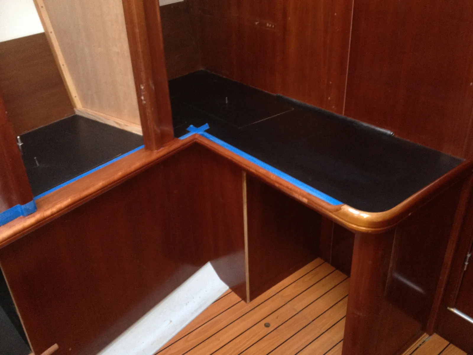 Finished black corner countertop with varnished wood trim in a sailboat interior refit