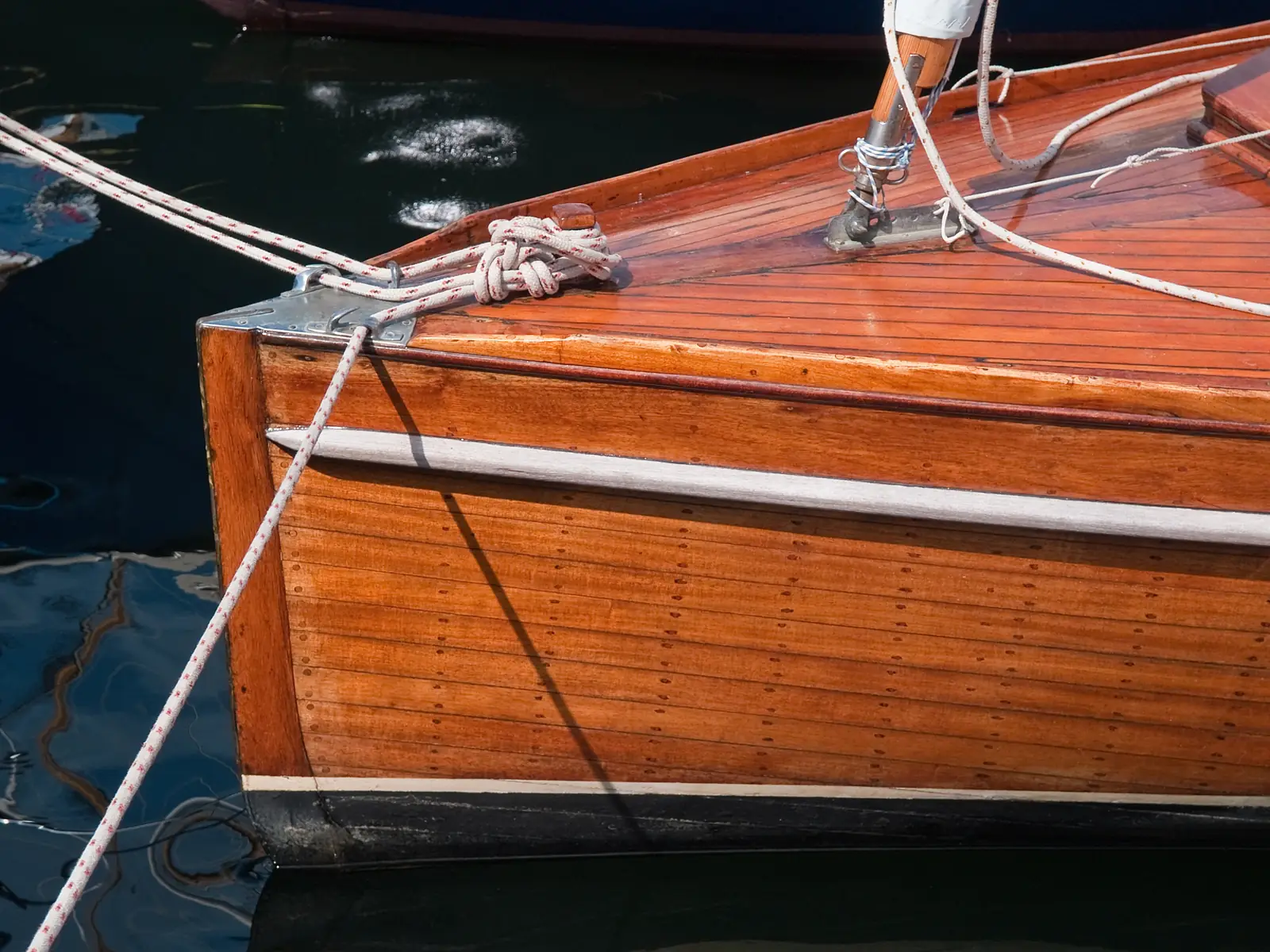 Restored yacht hull with varnished topsides at the dock